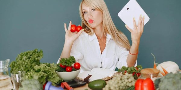 Vlogger promoting healthy eating with fresh vegetables on the table.